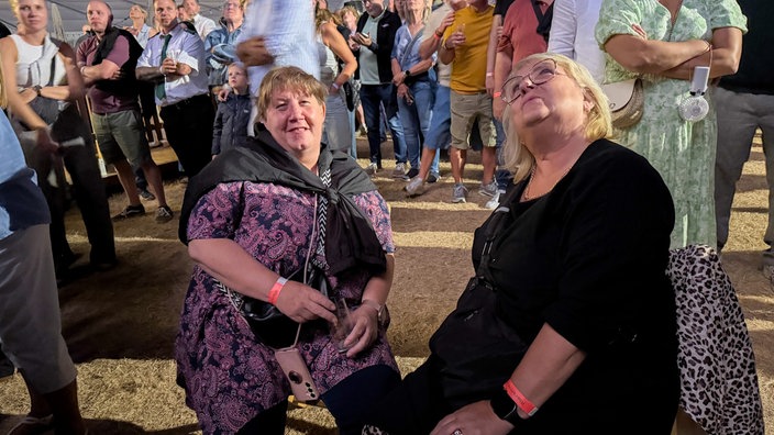 Zwei Frauen sitzen auf Stühlen bei der Rheinkirmes in Düsseldorf