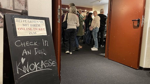 Menschen stehen an Kinokasse an