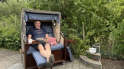 Ein Mann sitzt in einem Strandkorb.