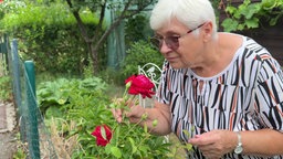 Eine Frau riecht an einer roten Rose