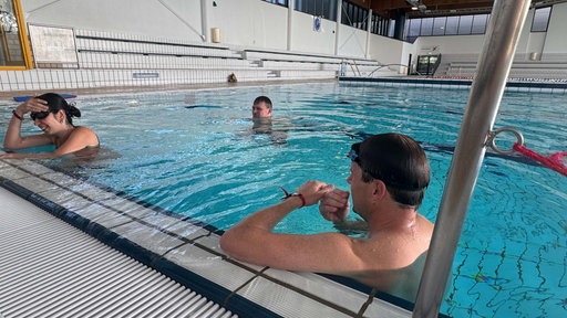 Schwimmlehrer Marc Pollok mit einer Schülerin und einem Schüler im Wasser im Rheinbad.
