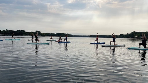 Menschen machen auf einem SUP-Board Yoga