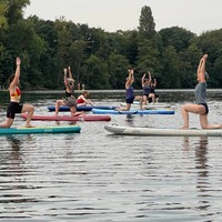 Auf einem See machen viele Menschen zusammen Yoga