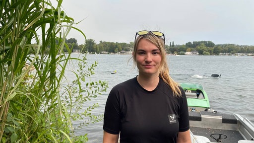 Eine Frau steht auf einem Steg und lächelt in die Kamera
