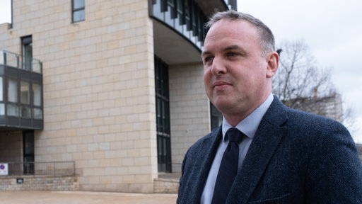 Ein Mann mit schwarzer Krawatte steht vor dem Düsseldorfer Landtag