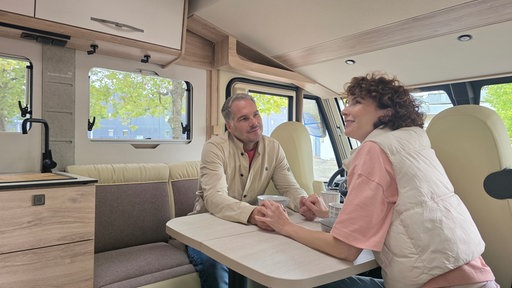 Zwei Menschen an einem Tisch in einem Campervan
