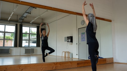 Yogalehrerin Kunie Baba zeigt vorm Spiegel eine Yoga-Pose.