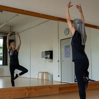 Yogalehrerin Kunie Baba zeigt vorm Spiegel eine Yoga-Pose.