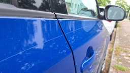 Blaues Auto mit einem großem Kratzer von der Hintertür bis zur Vordertür 