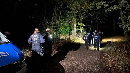 Polizisten laufen bei Nacht in ein Waldstück hinein