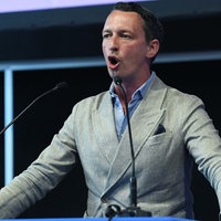 AfD-Politiker Matthias Helferich steht vor einem Podium und spricht in zwei Mikrofone.