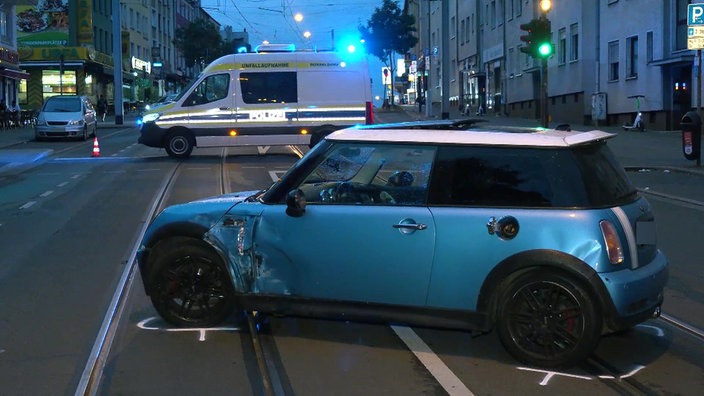 Nach einem Unfall steht ein Mini quer auf den Schienen der Altendorfer Straße in Essen. Im Hintergrund ist ein Einsatzwagen der Polizei zu sehen, der die Straße gesperrt.