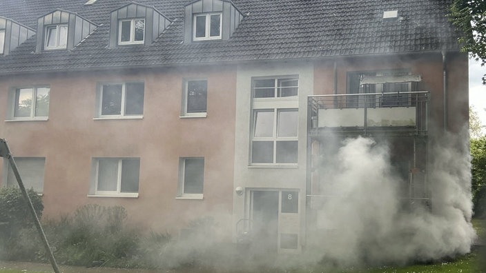 Um ein Mehrfamilienhaus ballen sich starke Rauchschwaden.