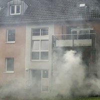 Um ein Mehrfamilienhaus ballen sich starke Rauchschwaden.