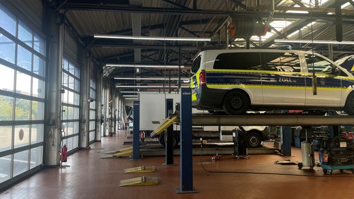 Die Werkstatt bei Daimler Truck. Auf dem Heber steht ein Wagen vom Zoll. Im Hintergrund sind Lastwagen zu sehen.