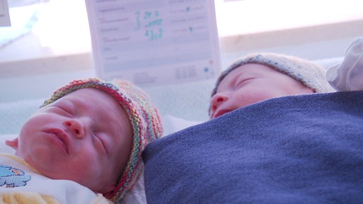 Zwei neugeborene Babys liegen nebeneinander auf einem Tisch