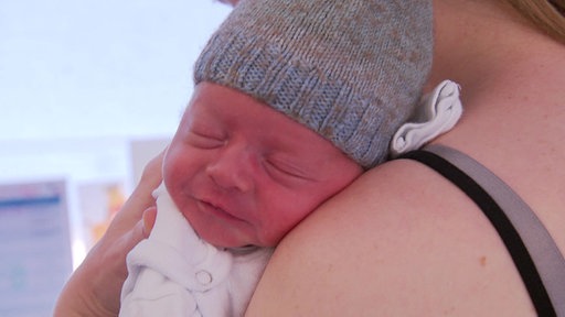 Ein Baby lehnt an der Schulter der Mutter 