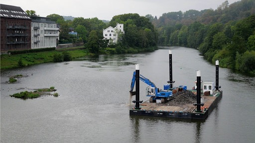 Ein Bagger auf einem schwimmenden Ponton gräbt unter Wasser in der Ruhr