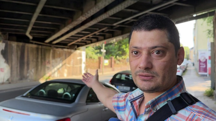Ein Mann steht unter einer Brücke der Deutschen Bahn.