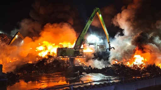 Ein Kran steht auf einem Schrottplatz, der in Flammen steht