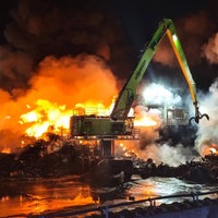 Ein Kran steht auf einem Schrottplatz, der in Flammen steht
