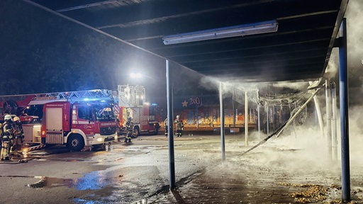 Die Feuerwehr Essen bei Nacht neben den qualmenden Überresten eines Pavillons