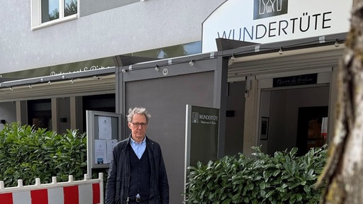 Ein Mann steht vor einem Lokal neben den Baken einer Baustelle