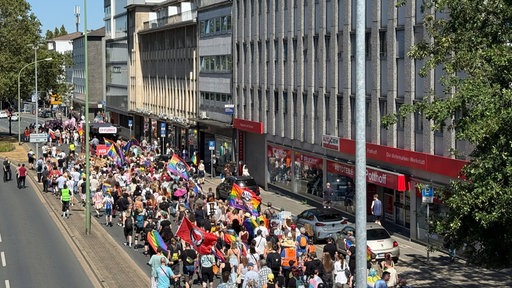 Zahlreiche Menschen ziehen mit Regenbogenfahnen und bunten Bannern durch die Essener Innenstadt beim RuhrPride.