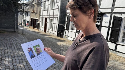 Tochter Alexandra Kallenberg hält einen Flyer in den Händen, auf dem Bilder ihrer vermissten Mutter zu sehen sind