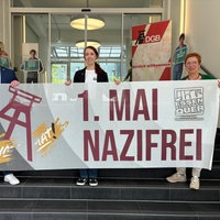 Ein Banner für die Gegendemo am 1. Mai wird präsentiert