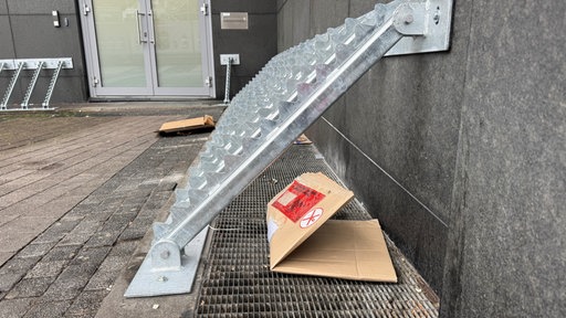 Ein silbernes Metallgitter, das aussieht wie eine liegende Leiter, ist fest an der Wand der Primark-Filiale angeschraubt.
