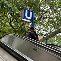 Schild einer U-Bahn-Station in der Essener Innenstadt mit Rolltreppe davor, auf der ein Fahrgast steht