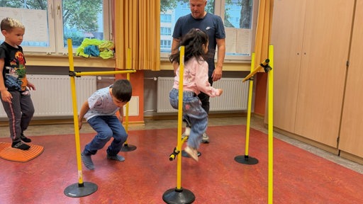Kinder und ein Mann bewegen sich in einem Klassenraum