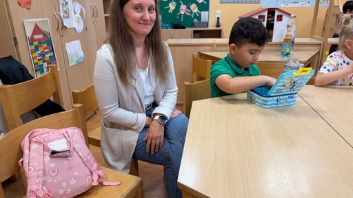 Eien Frau sitzt mit einem Jungen im Klassenraum