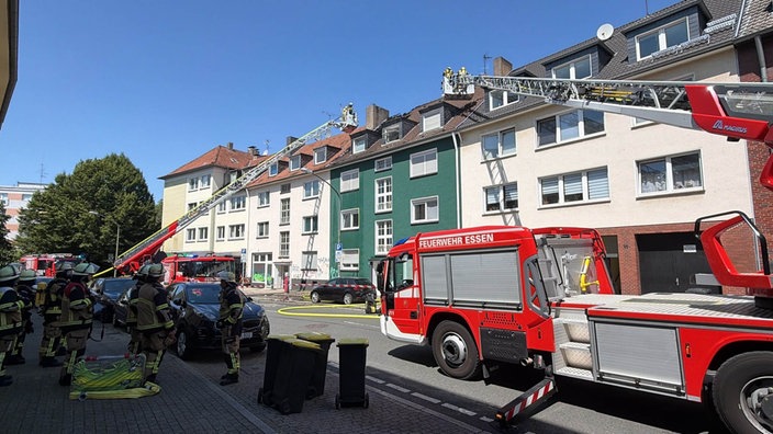 Zwei Leiterwagen der Feuerwehr stehen vor einem Haus im Essener Südviertel und löschen das Feuer in einem Dachstuhl