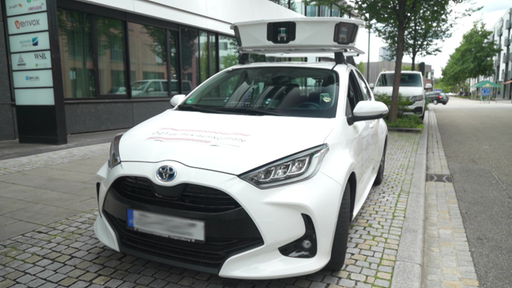Ein weißer Wagen parkt in einer Straße mit Kameras auf dem Dach