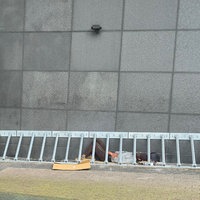 Eine Person liegt hinter einem Gitter an einer Hauswand