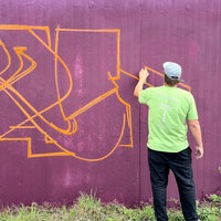 Ein Graffiti-Künstler besprüht die Stützwand einer Schallschutzmauer an einer Autobahn