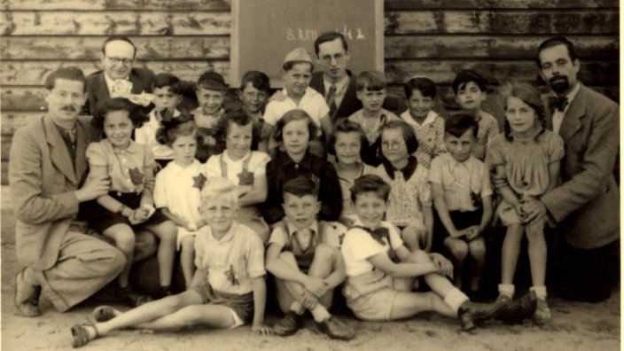 Ein historisches Klassenfoto aus dem Jahr 1942, Eva Weyl sitzt als kleines Mädchen auf dem Schoß des Lehrers, Wolfgang Polak sitzt in der ersten Reihe