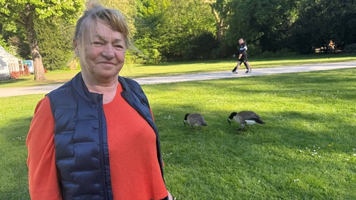 Eine Frau, Maria Chmielewska, steht im Schlosspark in Essen-Borbeck, im Hintergrund sind Kanadagänse zu sehen.