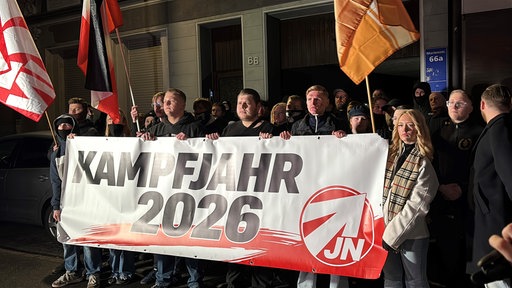 Mitglieder der rechtsextremen Jugendorganisation "Junge Nationalisten" in Essen Kray stehen mit Fahnen hinter einem Banner mit der Aufschrift "Kampfjahr 2026"