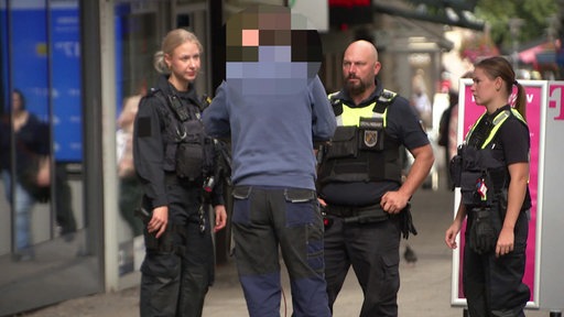Drei Polizisten stehen bei einem Mann der mit dem E-Scooter in der Innenstadt unerwegs war.