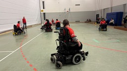 Mehrere Spieler spielen in ihren elektrischen Rollstühlen auf dem Feld. 