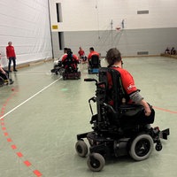 Mehrere Spieler spielen in ihren elektrischen Rollstühlen auf dem Feld. 