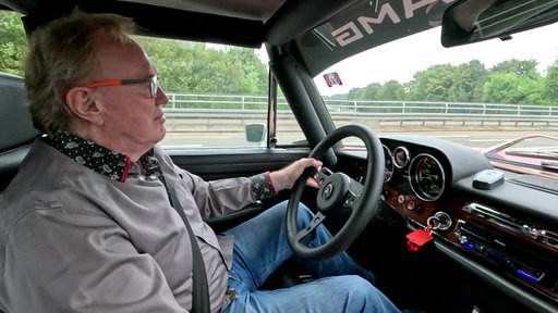 Paul Jüngst sitzt am Steuer seines Mercedes-Benz 300 SEL AMG.