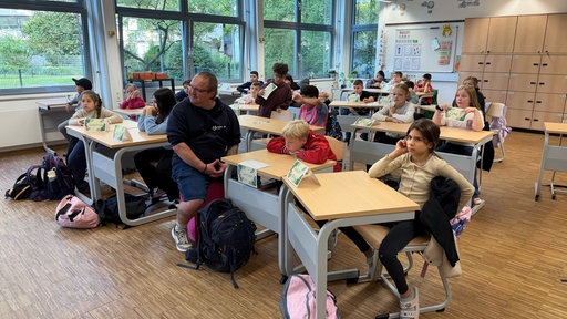 Schüler sitzen an Tischen im Klassenraum