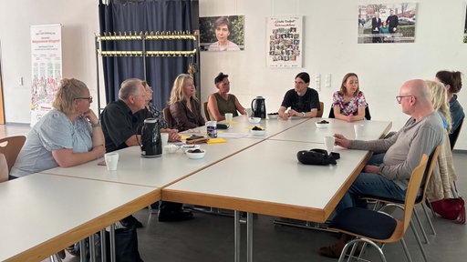 Mitglieder der Selbsthilfegruppe Wachkoma NRW in Gelsenkirchen sitzen zusammen an einem Tisch.