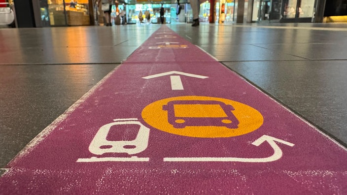 Ein roter Weg auf dem Boden führt zum Schienenersatzverkehr 