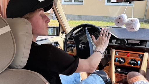 Junger Mann am Steuer eines alten Mercedes
