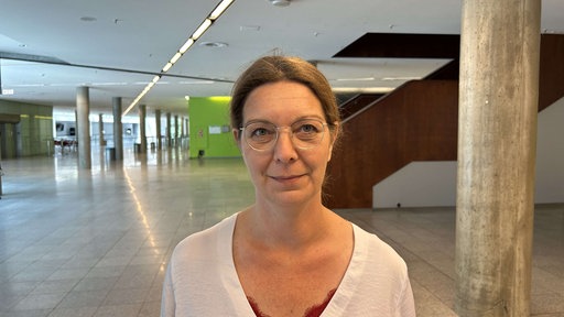 In dem Bild ist die Stadtverordnete Kathrin Schick zu sehen, die im Vordergrund steht und in die Kamera schaut